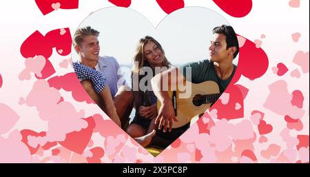 Image de cœurs sur des amis caucasiens heureux avec guitare sur la plage Banque D'Images