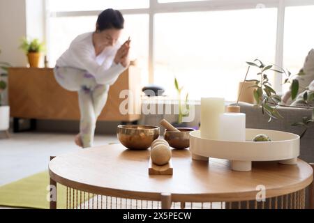 Bougies avec boules de massage et bol tibétain sur la table de femme sportive faisant du yoga à la maison, gros plan Banque D'Images