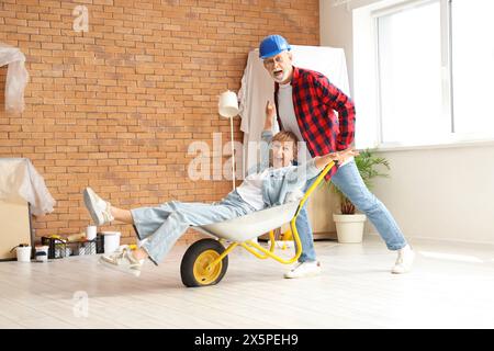 Couple mûr avec chariot s'amusant pendant la réparation dans la chambre Banque D'Images