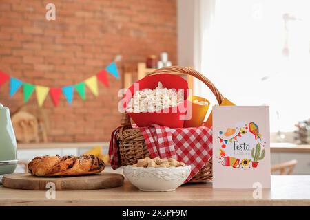 Panier de wicket avec pop-corn, cacahuètes et carte de voeux sur la table dans la cuisine. Fête de la Festa Junina Banque D'Images