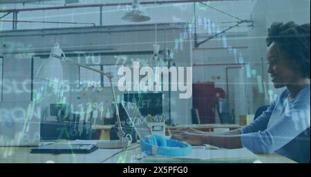 Image de graphiques et de tableau de trading sur une femme d'affaires afro-américaine travaillant sur un ordinateur portable Banque D'Images