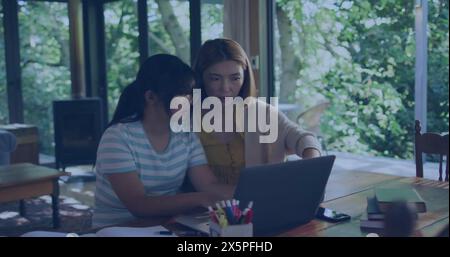 Mère asiatique et fille assise à table, regardant un ordinateur portable Banque D'Images