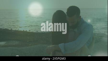 Image de taches de lumière contre un couple afro-américain s'embrassant à la plage Banque D'Images