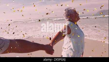 Image de confettis sur un couple senior diversifié heureux sur la plage Banque D'Images