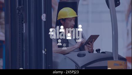 Image des icônes de profil sur le travailleur masculin caucasien utilisant la tablette assis dans le chariot élévateur à l'entrepôt Banque D'Images