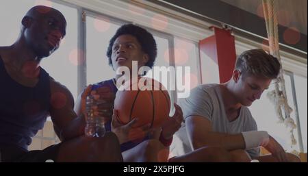 Deux Afro-américains et deux hommes caucasiens tiennent un basket-ball dans des tenues sportives Banque D'Images