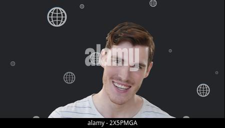Image de plusieurs icônes de globe Web flottant au-dessus de l'homme caucasien souriant sur fond gris Banque D'Images