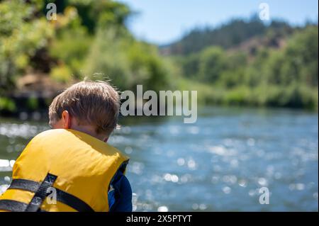 Focus sélectif sur un enfant descendant la sauvage et pittoresque Rogue River tout en portant un gilet de sauvetage Banque D'Images