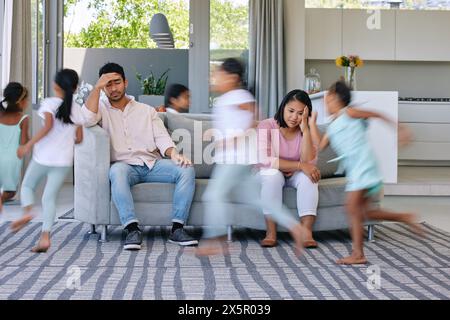 Les parents, la course et le stress à la maison, les enfants et fatigués avec l'épuisement professionnel, l'anxiété et le bruit dans un salon. Mère, père et enfants énergiques dans un Banque D'Images