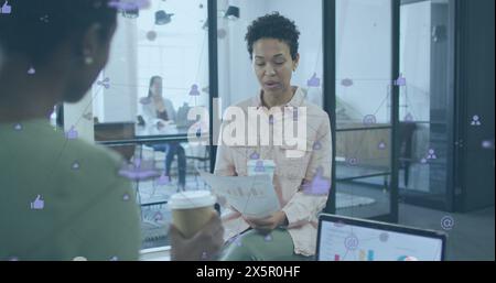 Image d'icônes connectées au-dessus de diverses collègues féminines discutant de rapports tout en buvant du café Banque D'Images