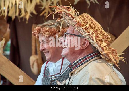 Baiona, Pontevedra, Galice, Espagne ; mars, 2023 ; Un homme et une autre femme artisan rient au festival Arribada, l'un avec un chapeau de paille et des fleurs Banque D'Images