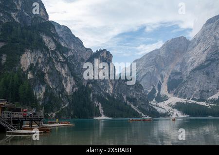 Emerald Lago di Braies est niché dans l'étreinte des Dolomites. La lumière du soleil danse sur l'eau turquoise, éclipsée par des sommets majestueux recouverts de pins. Un bateau en bois solitaire Banque D'Images