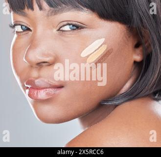 Femme noire, portrait et maquillage avec des nuances de fond de teint, de cosmétiques ou de teint sur un fond blanc de studio. Visage de la personne féminine africaine ou Banque D'Images