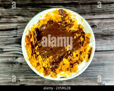 Sauce à la pâte de chocolat sur le dessus de la recette Sweet Koshary en Egypte faite de plusieurs couches de riz avec du lait pudding sucré, de la crème fouettée, du Konafa grillé et Banque D'Images