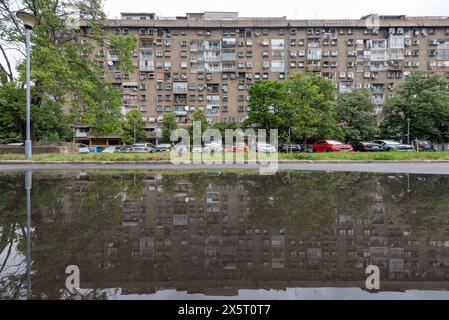 Architecture brutaliste dans un blok résidentiel sur le côté ouest de Belgrade, reflétée dans une grande flaque d'eau. Mai 2024. Banque D'Images