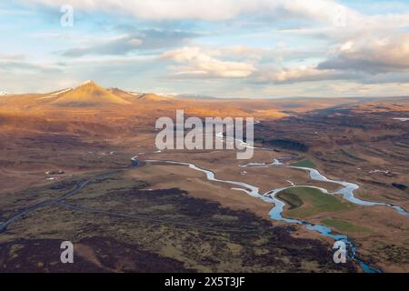 Vue panoramique sur le dron rivière sinueuse qui coule dans la prairie au printemps. Après le coucher du soleil. Borgarnes Islande. Banque D'Images