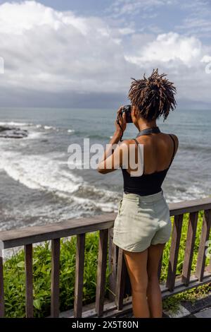 Indonésie, Bali, touriste femme photographiant la mer depuis le point d'observation Banque D'Images