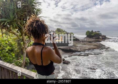 Indonésie, Bali, touriste femme photographiant la mer depuis le point d'observation Banque D'Images