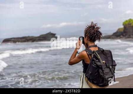 Indonésie, Bali, touriste femme photographiant la vue sur la mer Banque D'Images