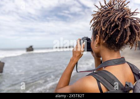 Indonésie, Bali, touriste femme photographiant la vue sur la mer Banque D'Images