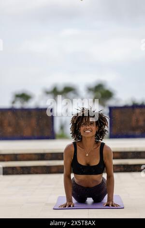 Femme souriante pratiquant la posture du chien face vers le haut Banque D'Images