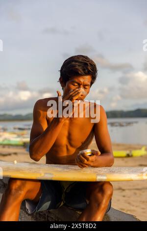 Indonésie, Lombok, surfeur masculin appliquant une lotion solaire sur le visage Banque D'Images