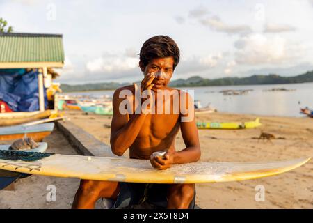 Indonésie, Lombok, surfeur masculin appliquant une lotion solaire sur le visage Banque D'Images