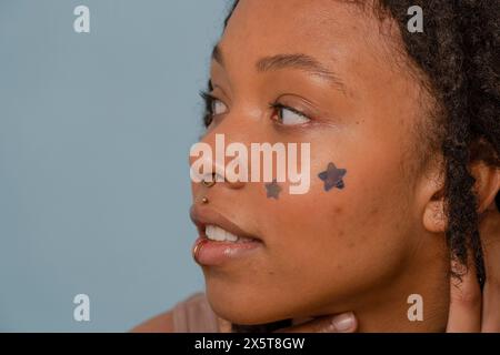 Gros plan d'une jeune femme portant des autocollants d'étoile sur le visage Banque D'Images