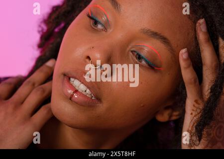 Jeune femme portant un eye-liner rose et des piercings Banque D'Images