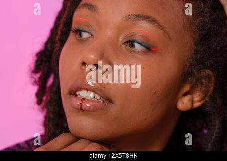 Jeune femme portant un eye-liner rose et des piercings Banque D'Images