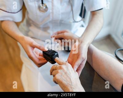 Médecin mettant l'oxymètre de pouls sur le doigt des patients Banque D'Images