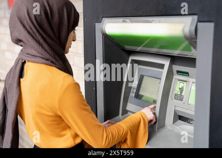 Femme en hijab utilisant ATM Banque D'Images