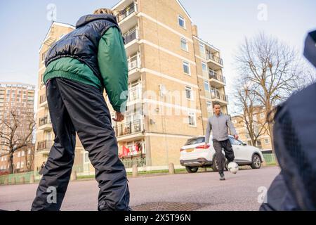 Jeunes amis masculins jouant au football en plein air Banque D'Images