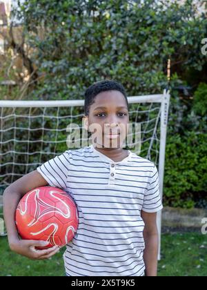 Portrait d'un garçon (8-9) tenant un ballon de football Banque D'Images