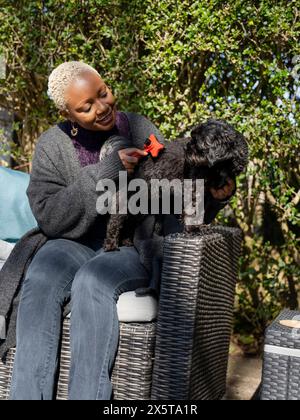 Femme brossant Shih Tzu Caniche dans le jardin Banque D'Images