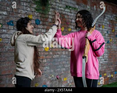 Jeunes femmes faisant high Five pendant l'entraînement au tir à l'arc Banque D'Images