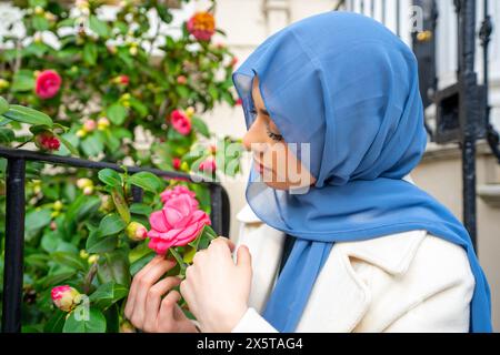 Jeune femme portant le hijab qui sent des fleurs Banque D'Images