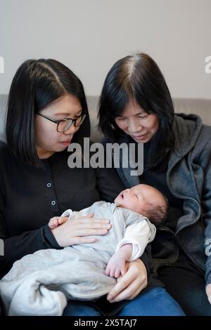 Mère et grand-mère regardant bébé fille (0-1 mois) à la maison Banque D'Images