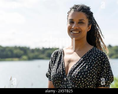 Portrait de femme souriante debout par le lac jour ensoleillé Banque D'Images