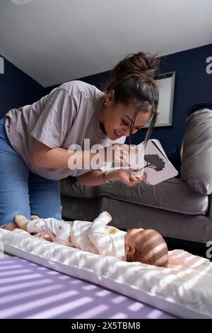 Mère montrant des cartes contrastées à la petite fille nouveau-né à la maison Banque D'Images