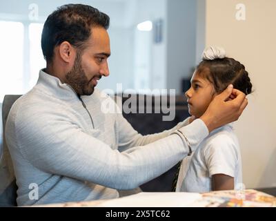 Père aidant son fils (6-7) à se préparer pour l'école Banque D'Images