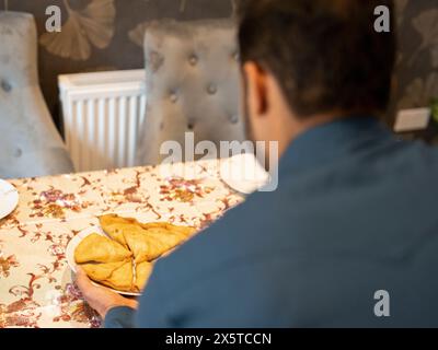 Homme mettant de la nourriture sur la table Banque D'Images