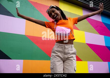 Jeune femme souriante sautant contre un mur coloré Banque D'Images