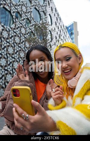 Jeunes amis souriants ayant un appel vidéo Banque D'Images