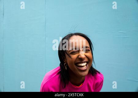 Jeune femme en sweat-shirt rose riant à l'extérieur Banque D'Images