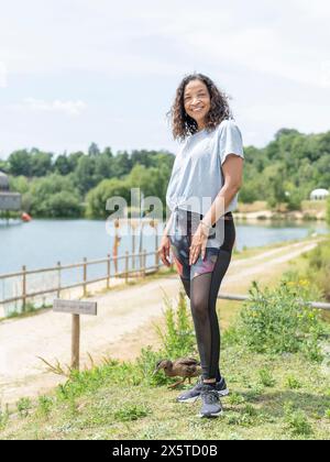 Portrait d'une femme souriante debout près du lac Banque D'Images