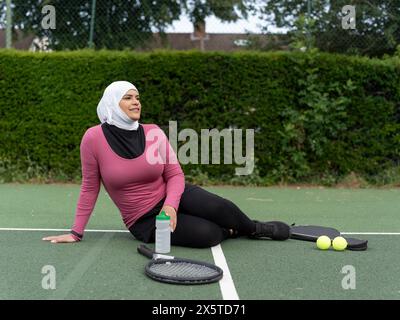 UK, Sutton, femme en foulard reposant sur un court de tennis Banque D'Images