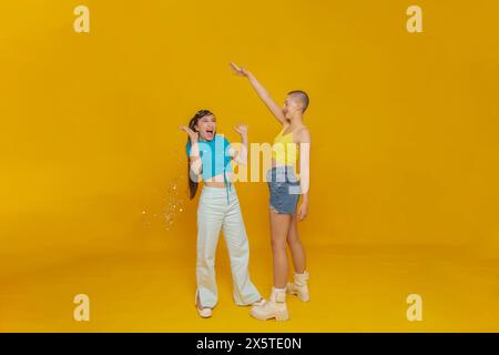 Portrait studio d'amis élégants souriants avec des confettis Banque D'Images