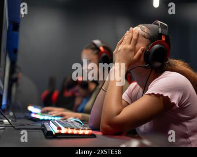 Amies féminines jouant à des jeux vidéo dans un club de jeu Banque D'Images