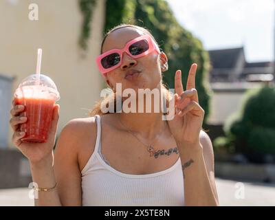 Portrait de jeune femme en lunettes de soleil avec smoothie Banque D'Images